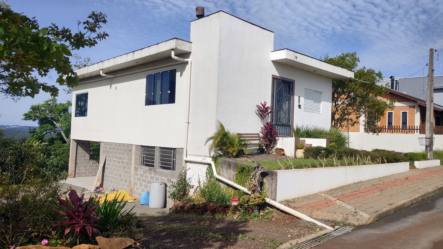 A frente da casa, com o jardim e a calçada em paver